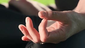 Young female with tattooed arms sits in lotus pose with fingers showing root chakra. Lady practices yoga and meditates in city park in morning slow motion - Powered by Shutterstock - Get 15% off with code: PIKWIZARD15