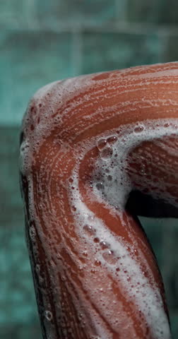 Soap, bathroom and legs of woman in shower for cleaning, washing body and grooming in home. Sponge, beauty and person with satisfaction, hygiene and daily routine for skincare, wellness and health