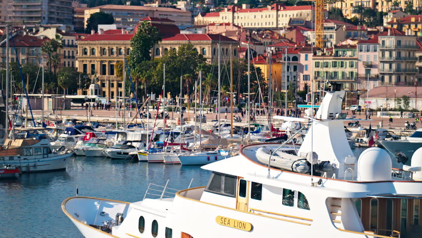 Cannes, France - February 10, 2025: Boats docked in the Vieux-Port the mountains on the background