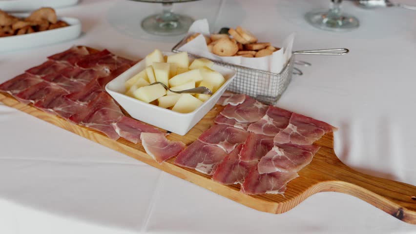 Cured ham with melon cubes served on a wooden board at a catered event or gathering