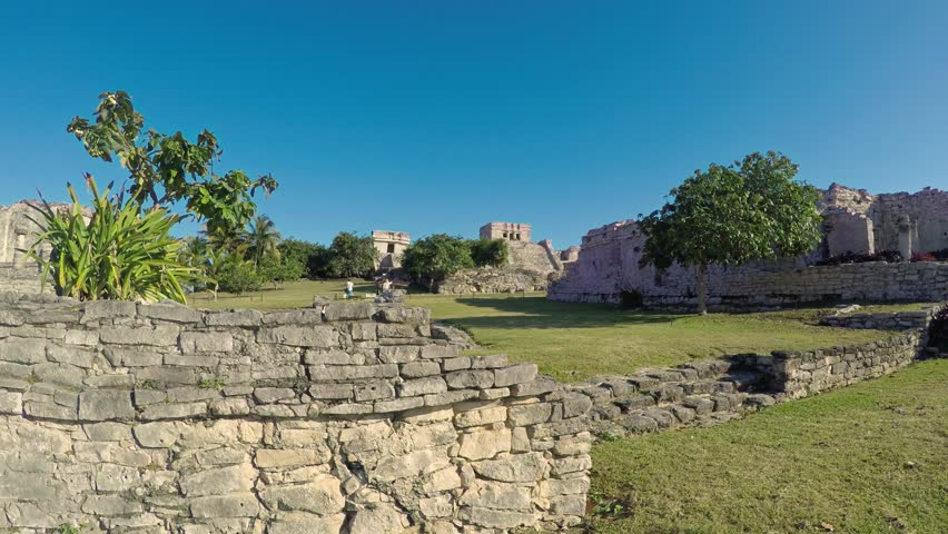 Stone walls and lush vegetation frame the ancient mayan ruins of tulum, a captivating archaeological site overlooking the caribbean sea in mexico