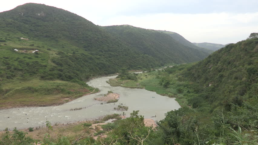 An extreme long shot of the Umkomaas river and  lush green trees along the river