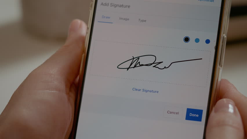 Woman is using her smartphone to create a digital signature. She carefully gestures with her finger on the screen while focused on the task.