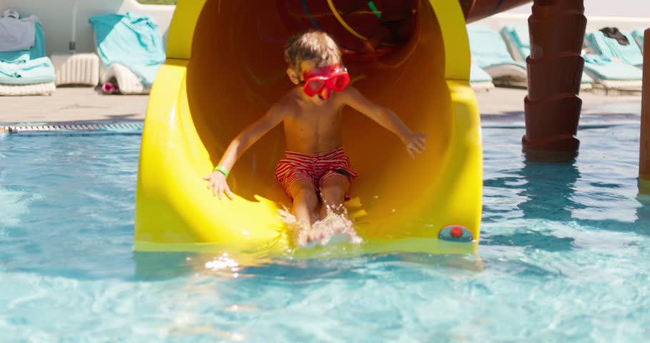 Child sliding down yellow water slide at pool 