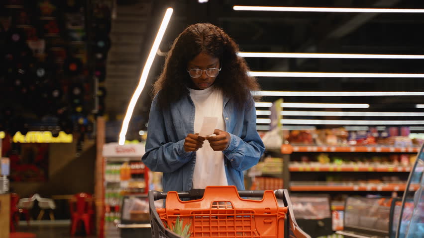 African American woman shocked by prices while checking receipt