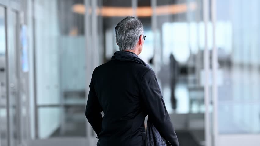 Gentleman in tuxedo coming outdoors through the automatic doors of the facility.