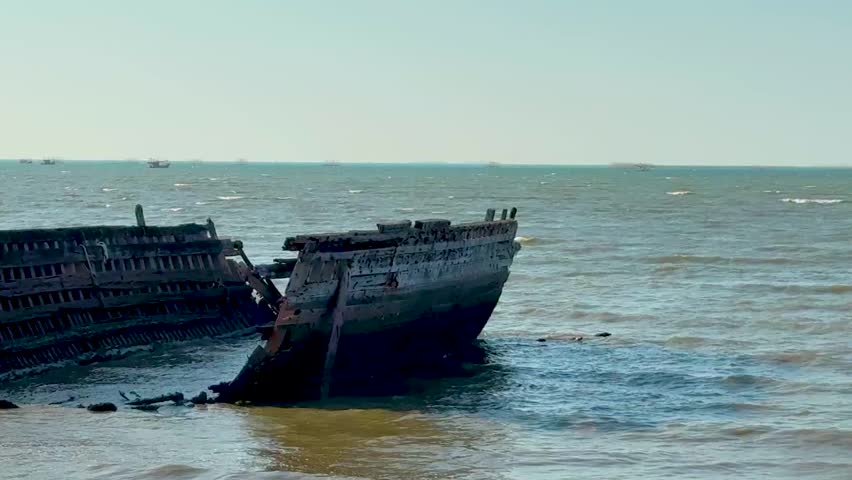 A decaying shipwreck leans against the gentle waves, creating a serene maritime scene.