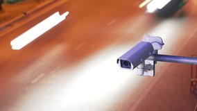 Surveillance enforcement camera monitor city traffic and speed control watching cars driving in the background. Timelapse long exposure effect - Powered by Shutterstock - Get 15% off with code: PIKWIZARD15
