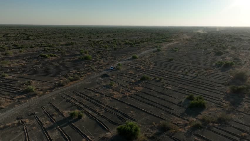 Forward moving drone shot of barren land with wild bushes scattered at a village near Sukkur in Sindh, Pakistan.