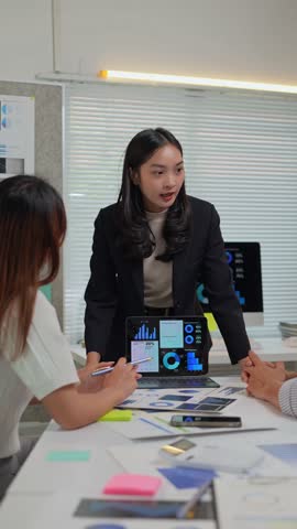 Confident businesswoman presenting project results to colleagues, engaging in productive teamwork while analyzing charts and data on a laptop in a modern office setting