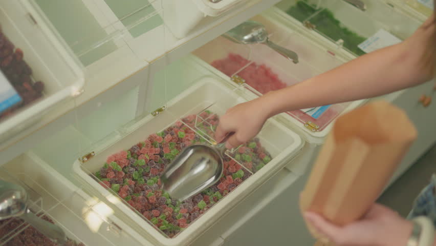 Female customer fills cereal foods in a glass jar, lever the reusable container on refill store shelves, zero-waste and plastic-free grocery, environment-friendly, sustainable lifestyles.