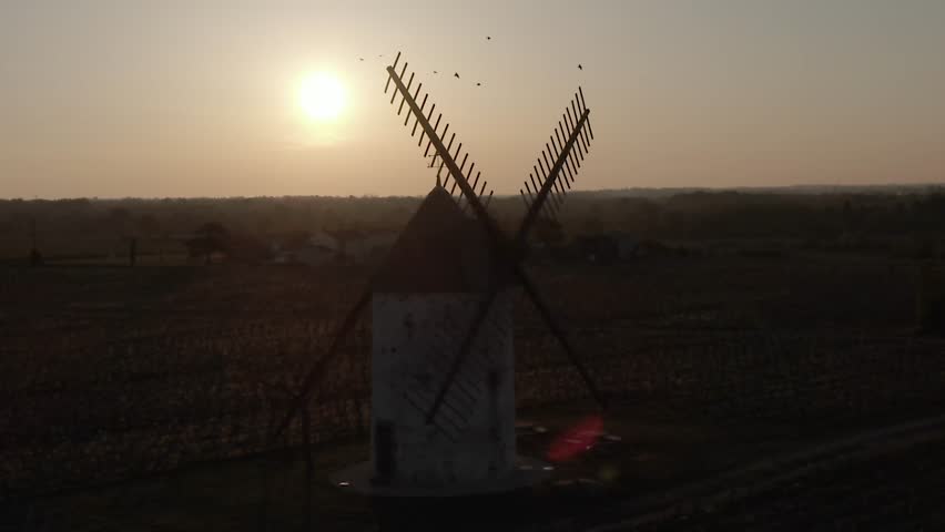 Drone flying close to windmill blades, rural landscape, Saint-Vincent-sur-Graon at sunset, France. Aerial drone lateral view, close-up