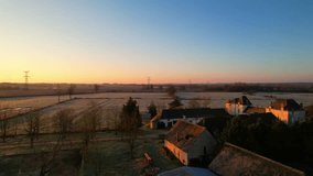 Peaceful aerial view of a traditional French farm bathed in warm sunrise light. Frost-covered fields, rustic buildings, and countryside charm create a serene morning scene. - Powered by Shutterstock - Get 15% off with code: PIKWIZARD15