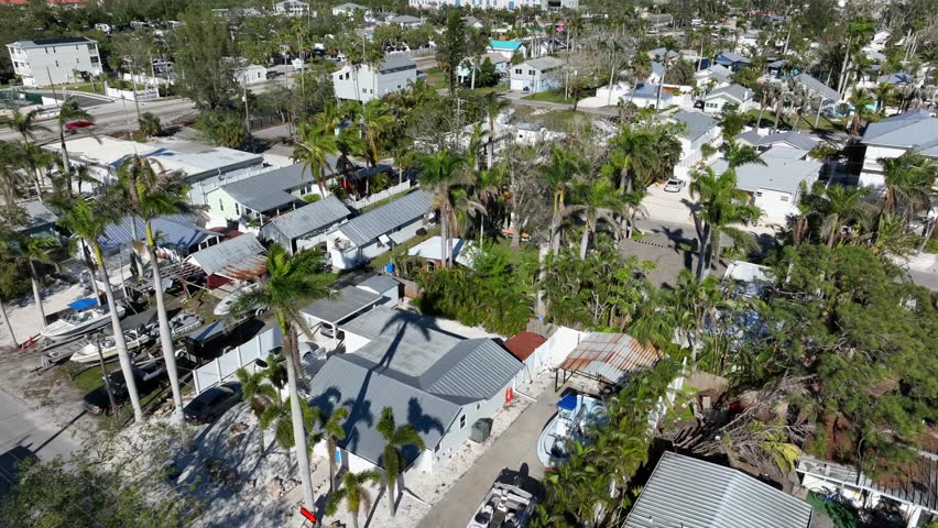 Houses and homes with swimming pool and palm trees on street in Bradenton, FL. Aerial flyover shot. Traffic on main street, Luxury neighborhood in Florida.