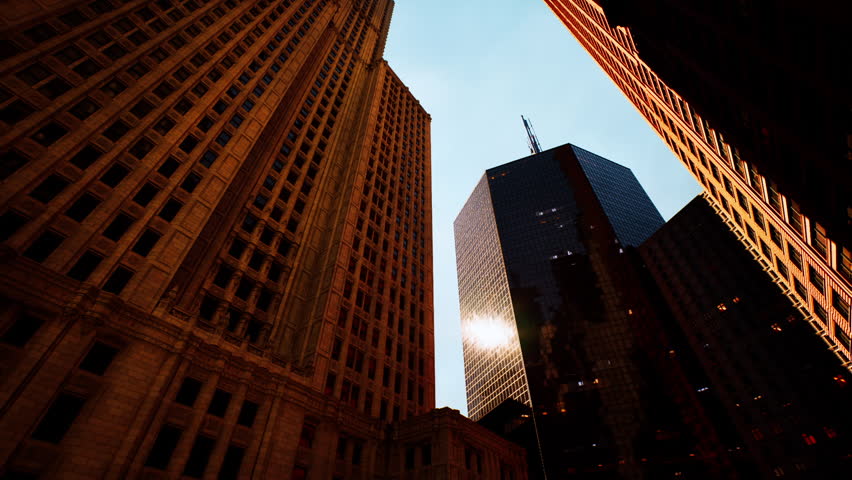 The sun sets behind towering skyscrapers, casting long shadows on the streets below. The vibrant reflections on the glass facades create a dramatic urban atmosphere.