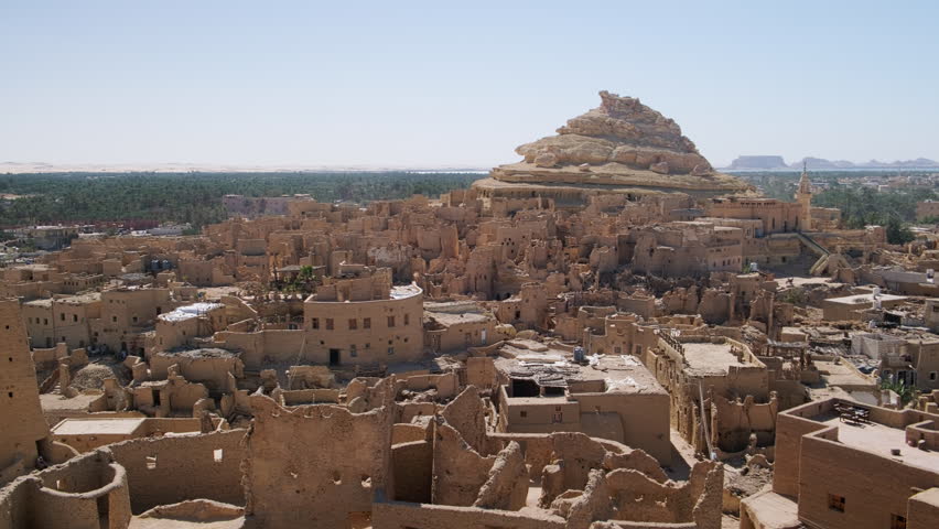 Remains of mud-brick houses of Shali fortress and Shali Mountain at background in Siwa Oasis, Egypt. Panning real time footage