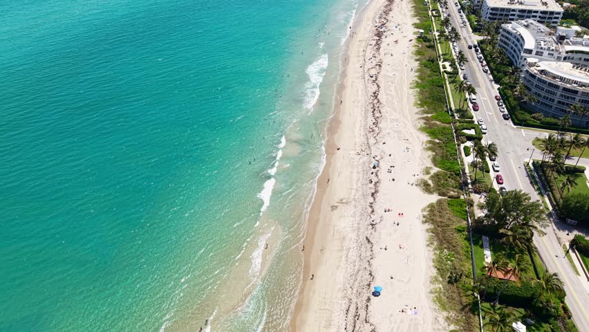 Reveal drone shot of turquoise water of Atlantic Ocean and beach near Municipal Beach during the day in West Palm Beach, Florida, USA