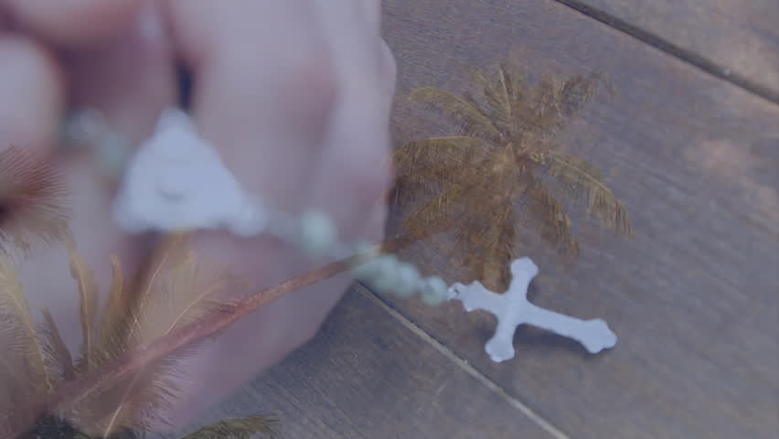 Holding rosary beads, hands overlaid with palm trees creating serene animation. Tranquility, meditation, spirituality, faith, prayer, nature