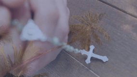 Holding rosary beads, hands overlaid with palm trees creating serene animation. Tranquility, meditation, spirituality, faith, prayer, nature - Powered by Shutterstock - Get 15% off with code: PIKWIZARD15