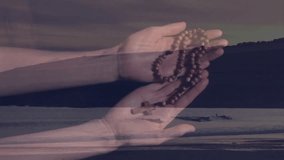 Holding rosary beads, hands against serene beach landscape with distant figure. Prayer, spirituality, meditation, ocean, tranquility, solitude - Powered by Shutterstock - Get 15% off with code: PIKWIZARD15