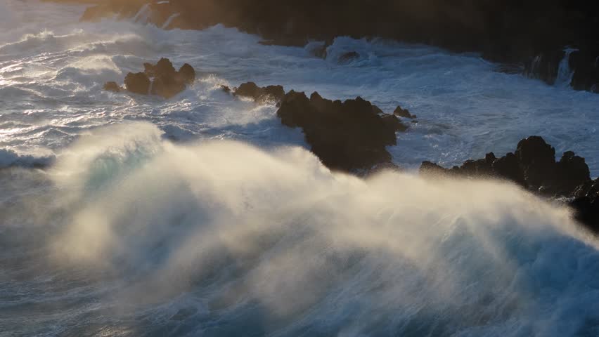 Huge power ocean wave crashing over sunset sky background. Slow motion of stormy ocean surf splashing on the coast of Madeira, Porto Moniz