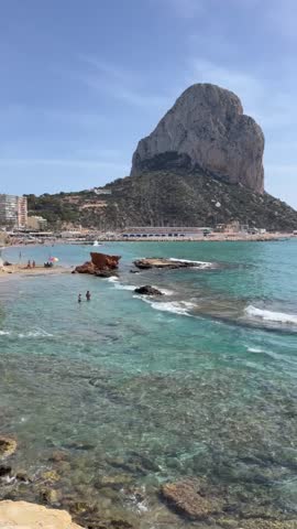 Cliff Penyal d'Ifac Natural Park in Calpe. View of the cliff from the coastline in sunny warm day. Beach and blue sea in Spain. Costa Blanca, Alicante province.Vertical video