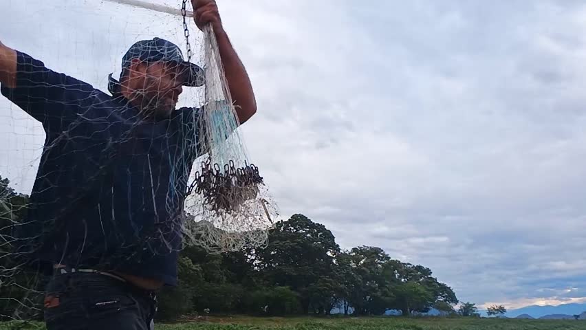A colombian fisherman casting a cast net at the Betania dam in Yaguara, Huila, Colombia. Concept of work and artisanal fishing