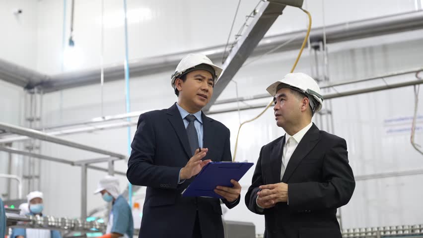 Businessman owner and partner discuss operations while inspecting food production line in canned fish factory