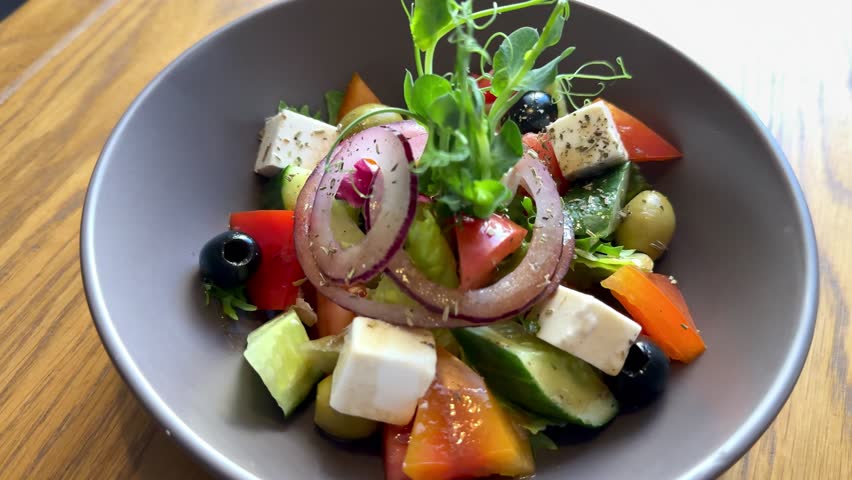 Greek salad with fresh vegetables tomatoes, cucumbers, onions, olives, feta cheese on a plate in a restaurant