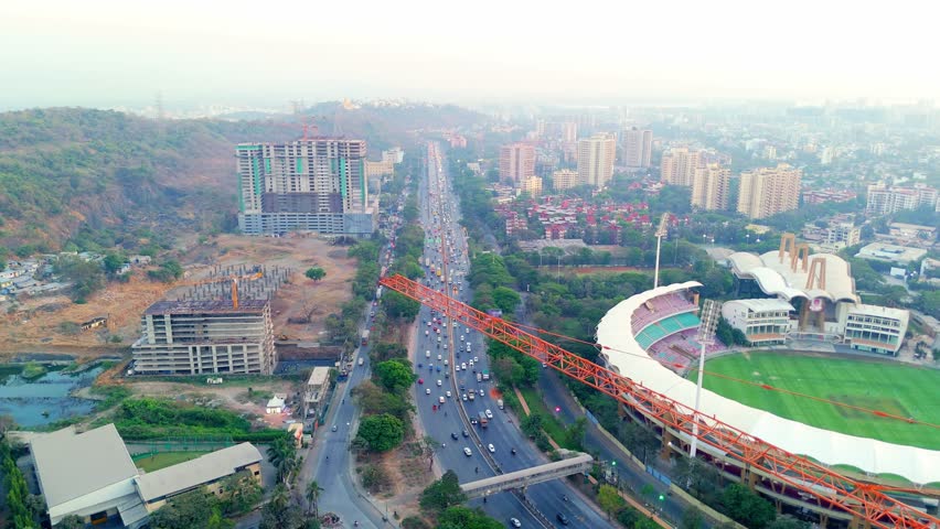 Aerial shot reveals busy highways and moving vehicles, Drone view bustling expressway in metropolis, Roadways packed into traffic near sports stadium, City drive link modern towers with old districts