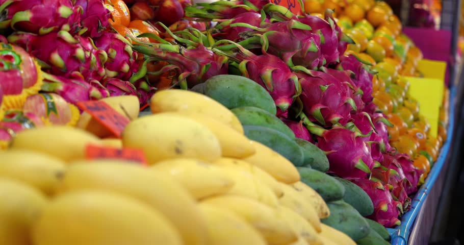 Colorful tropical fruits market stall, mangoes dragon fruits oranges, Thailand market fresh produce exotic food vibrant display healthy eating.