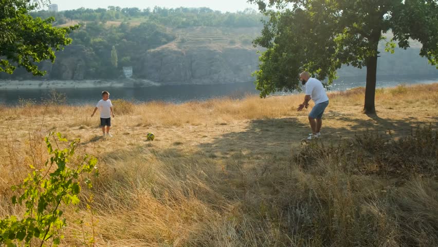 Father and son playing football outdoors. Fun on a picnic