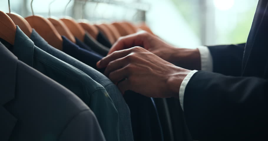 Clothes, shopping and retail with hands of person in boutique show room for fashion, tailor and wardrobe. Decision, designer and sale with closeup of rail in store mall for textile, fabric and search