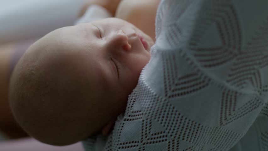 Close-up, mother lulls her newborn baby to sleep by rocking him in her arms. Healthy sleep. Motherhood. Mother's Day. Family. Childbirth. Slow motion video 4K