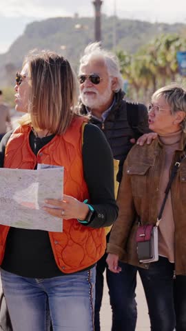 Vertical. Group diverse tourist people walking with suitcases together looking paper map enjoying sunny autumn vacations. Adults friends strolling talking happy sightseeing in city on holiday travel