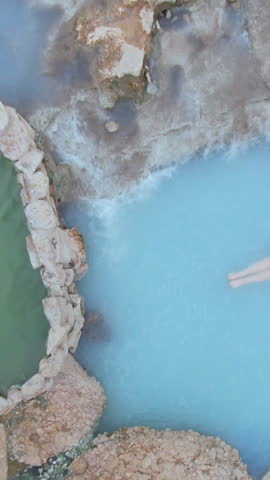 AERIAL, TOP DOWN: Flying above tourists taking a relaxing bath in hot springs in Utah. Hikers exploring Utah stop and take a therapeutic bath in the hot river running across the rugged snowy landscape