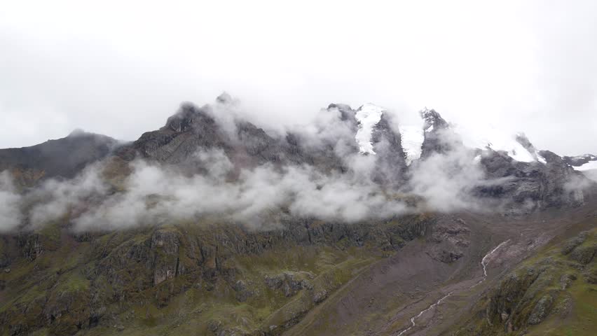 Snowy Mountain with Clouds Around it and a Stream Flowing from the Snowmelt