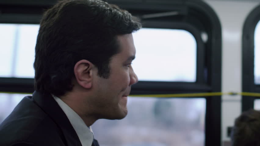 Man in a suit, riding the bus. Close up. He gets up to get off at the end of the