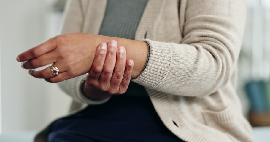 Old woman, hands and arthritis for wrist pain in home, massage joint and inflammation or disease. Senior person, sprain and swollen muscle by chronic fibromyalgia, hurt and osteoporosis or rheumatism