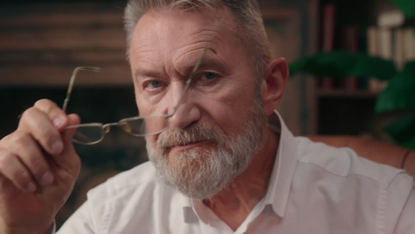Portrait Caucasian old man grandfather pensioner elderly aged male senior takes off eyeglasses looking at camera health sight indoors gaze vision medicine confident serious businessman business home