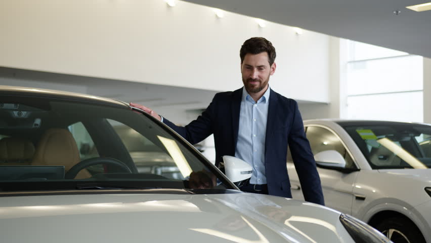Caucasian man client buyer customer choosing examine dreaming excited male auto showroom touch new car transport vehicle purchase guy businessman business buying shopping decision rental service store