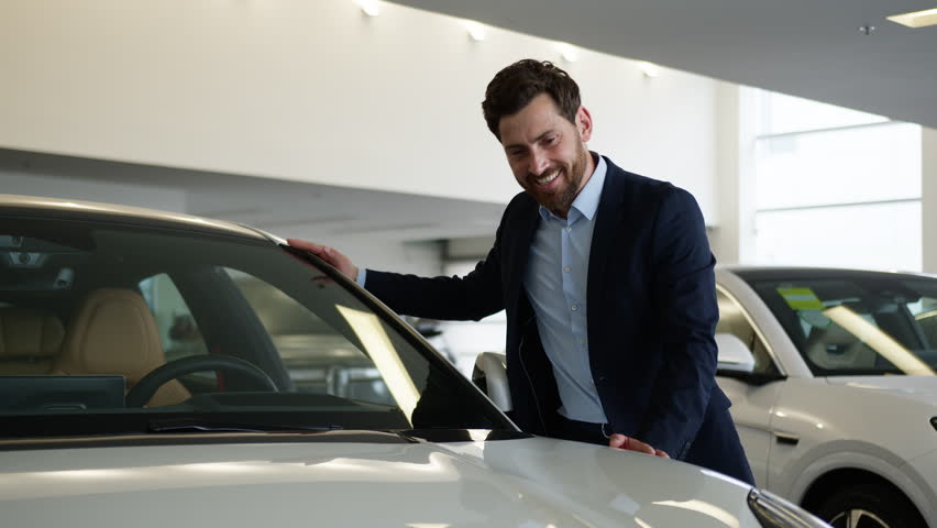 Caucasian man client buyer customer choosing examine dreaming excited male auto showroom touch new car transport vehicle purchase guy businessman business buying shopping decision rental service store