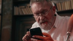 Old Caucasian man using mobile phone smartphone cellphone zooming slide fingers screen glasses health medicine vision male businessman business pensioner mature senior home office indoors online app - Powered by Shutterstock - Get 15% off with code: PIKWIZARD15