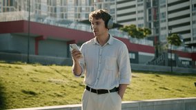 Happy Caucasian young man listening music on headphones energetic carefree male city guy dancing moving song playlist audio weekend pleasure mobile phone student businessman technology outdoors fun - Powered by Shutterstock - Get 15% off with code: PIKWIZARD15