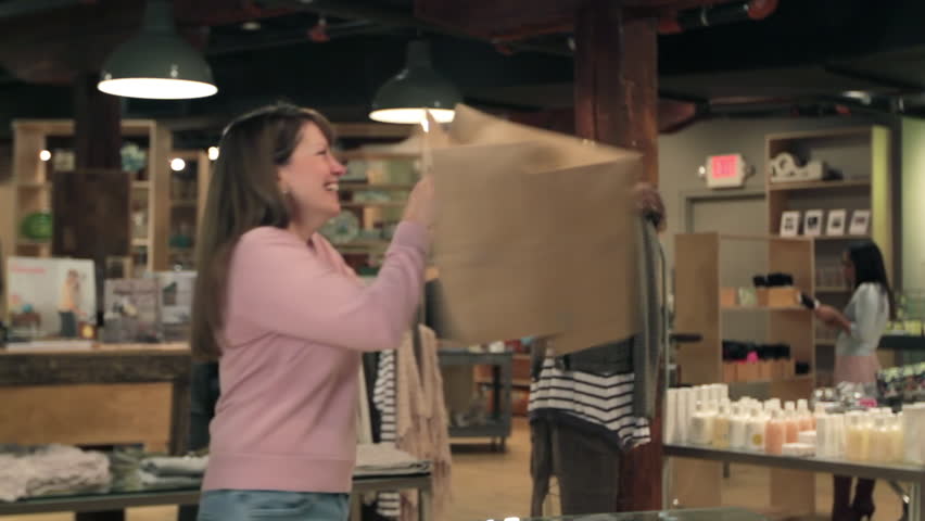 Happy shopper spins as she leaves the boutique's checkout with her shopping