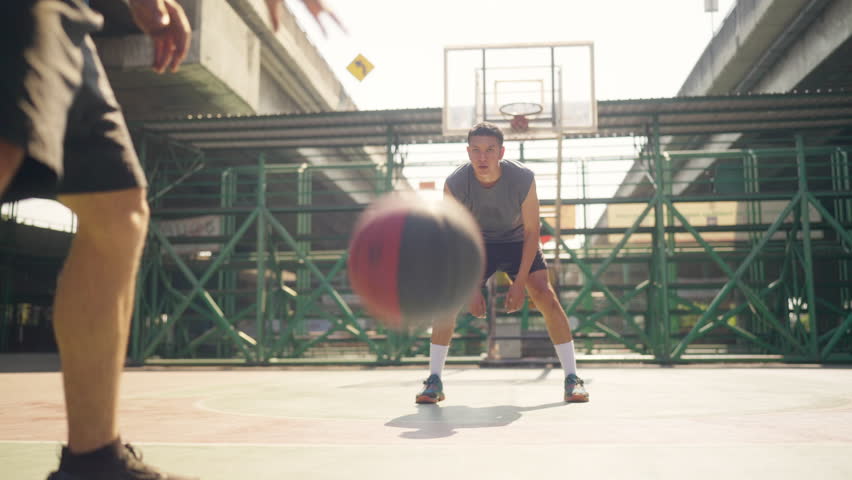 Wellness outdoor sport training street basketball. Two strong sportsman basketball player playing streetball match at outdoor court in the city. Male athlete do fitness workout exercise in sunny day.