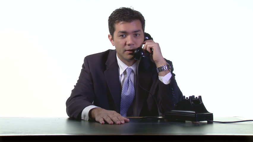 Business man in white studio talking on a retro phone and making lots of hand