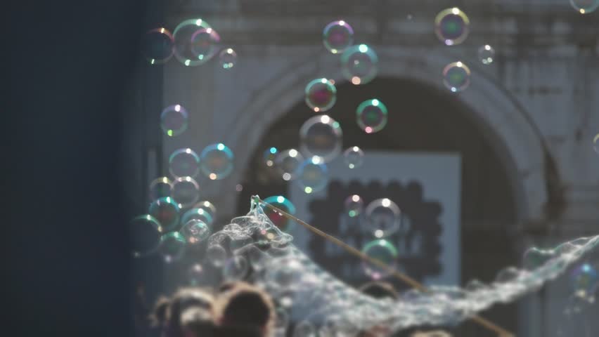 Street performer creating large soap bubbles for a crowd