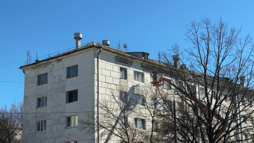 Workers Repairing the Exterior of a Residential Building in a Clear Blue Sky