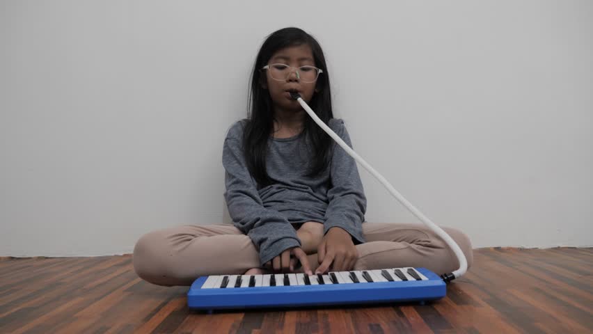 Asian little girl playing pianica, melodica blow organ musical instrument